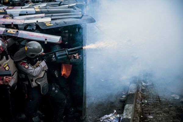 ضابط شرطة يستخدم الغاز المسيل للدموع خلال اشتباك مع الطلاب المحتجين ضد قانون جديد ضد محاربة الفساد في باندونغ، إندونيسيا 30 سبتمبر 2019 - سبوتنيك عربي