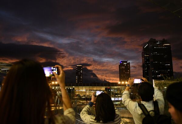 مواطنون يلتقطون صور للسماء غروب الشمس أثناء اقتراب الاعصار هاغيبيس في أوساكا، اليابان 12 أكتوبر 2019 - سبوتنيك عربي
