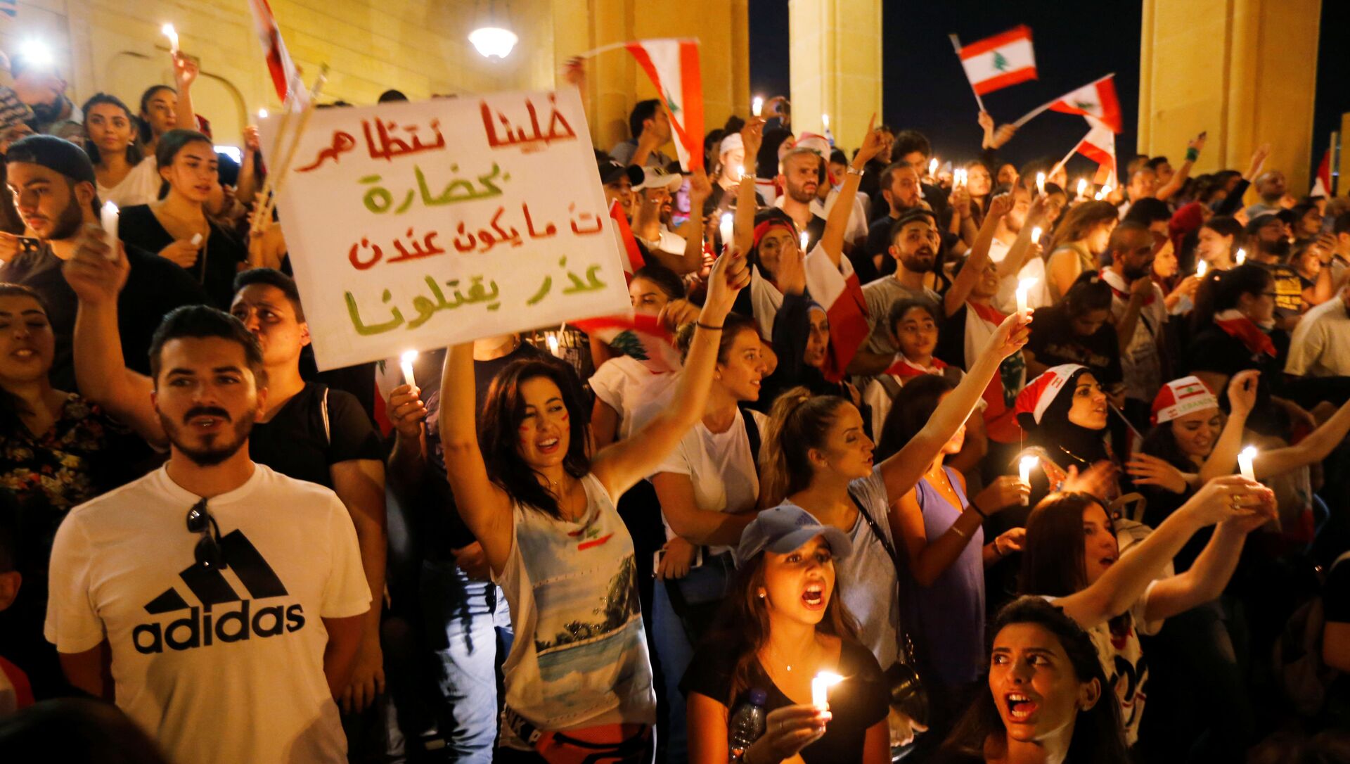 المتظاهرون يحملون أعلاماً وطنية ويضيؤون الشموع أثناء مظاهرة مناهضة للحكومة بالقرب من مسجد الأمين في بيروت - سبوتنيك عربي, 1920, 19.10.2021