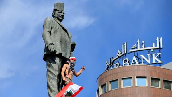 أحد المتظاهرين يلوح أثناء وقوفه في تمثال رياض الصلح أثناء مظاهرة مناهضة للحكومة بالقرب من قصر الحكومة في بيروت - سبوتنيك عربي
