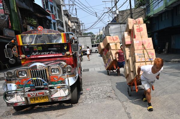 عمال يجرون عربات محملة بالبضائع على طول شارع في الحي الصيني في مانيلا، 22 أكتوبر 2019 - سبوتنيك عربي