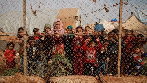 أطفال سوريون مهجرون يقفون خلف سياج مخيم كفر لوسين، في ريف إدلب الشمالي، الحدود السورية التركية، 22 أكتوبر 2019 - سبوتنيك عربي