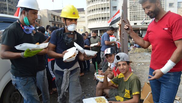 أطفال يتناولون أطباقا من وجبة برياني دجاج، توزع مجانا على المتظاهرين، في التحرير، بغداد - سبوتنيك عربي