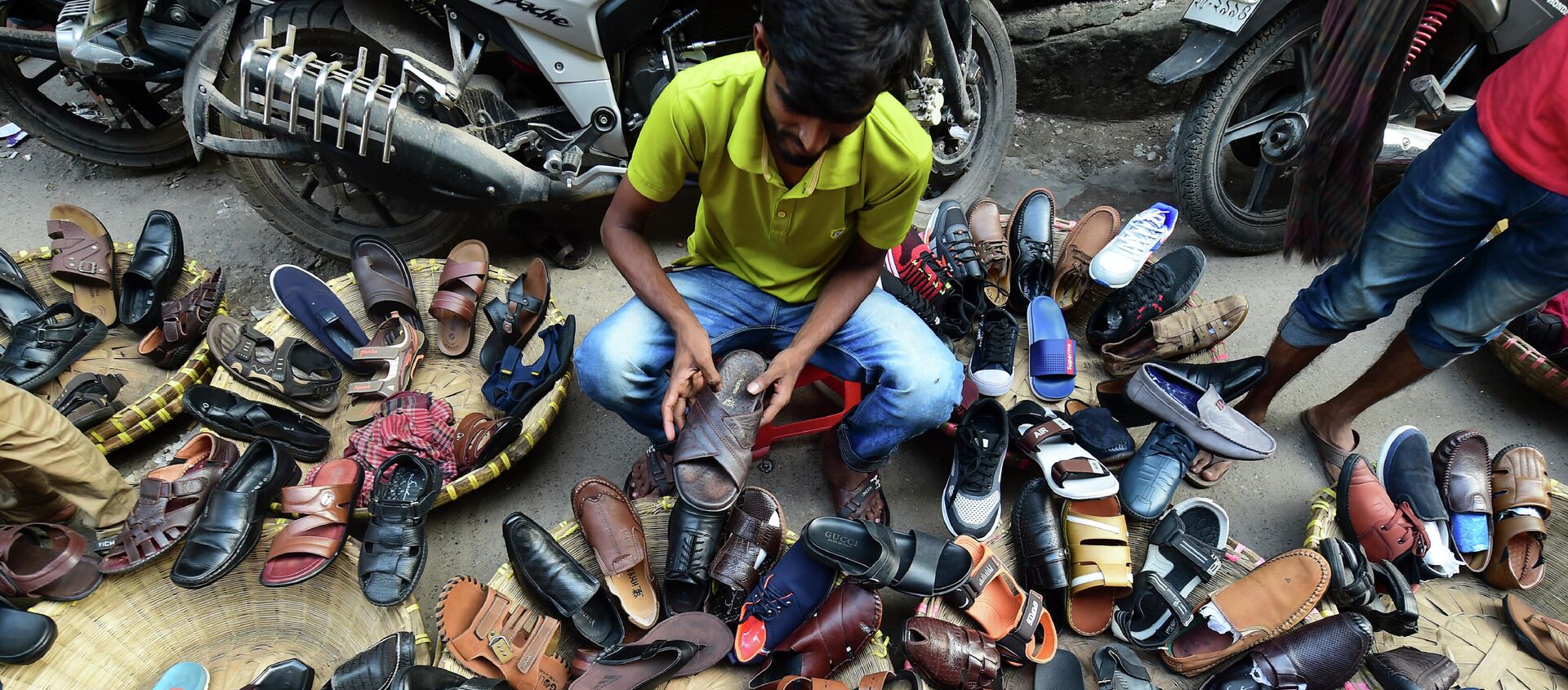بائع أحذية في الشوارع من بنغلاديش يرتب الأحذية وهو يستعد لعرضه في دكه في 30 أكتوبر 2019 - سبوتنيك عربي, 1920, 02.09.2021