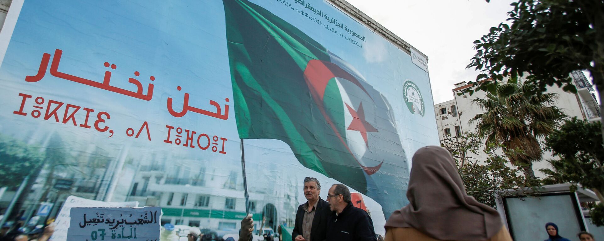 أشخاص يمشون بجوار ملصق حملة للانتخابات الرئاسية في الجزائر العاصمة - سبوتنيك عربي, 1920, 06.10.2020