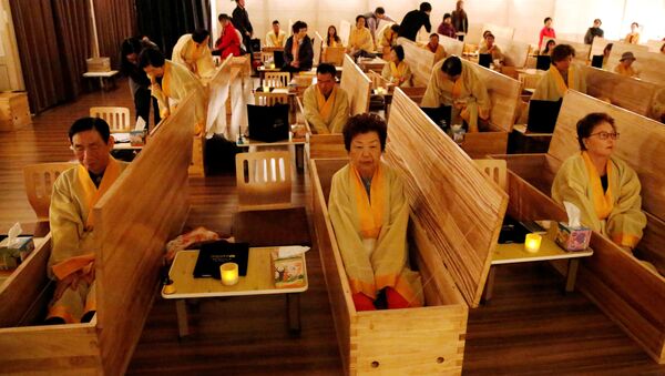 Participants sit inside coffins during a living funeral event as part of a dying well programme, in Seoul, South Korea - سبوتنيك عربي