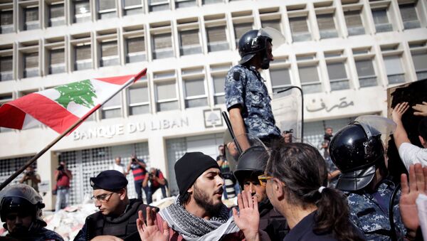 ضباط الشرطة يقفون حذرًا بعد أن قام المتظاهرون بهدم السياج أثناء تظاهرهم خارج البنك المركزي اللبناني خلال الاحتجاجات المستمرة المناهضة للحكومة في بيروت - سبوتنيك عربي