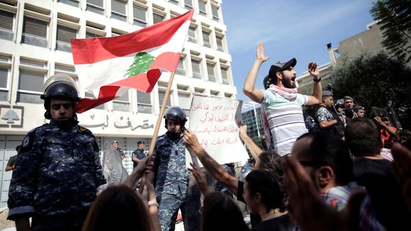 ضباط الشرطة يقفون حذرًا بعد أن قام المتظاهرون بهدم السياج أثناء تظاهرهم خارج البنك المركزي اللبناني خلال الاحتجاجات المستمرة المناهضة للحكومة في بيروت - سبوتنيك عربي