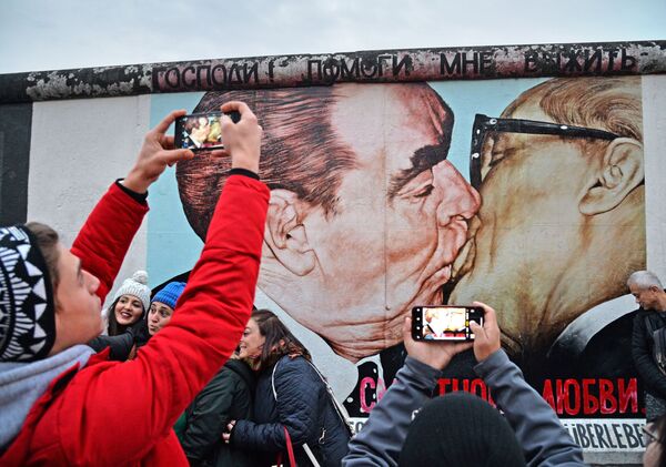 جدارية - رسم غرافيتي للزعينم السوفيتي بريجنيف وقائد جمهورية ألمانيا الديمقراطية (ألمانيا الشرقية) إريش هونيكر على الجزء المتبقى من جدار برلين (East-Side Gallery)، حيث يتجمع المواطنون والسياح بمناسبة مرور الذكرى الـ 30 لإسقاط الجدار. - سبوتنيك عربي