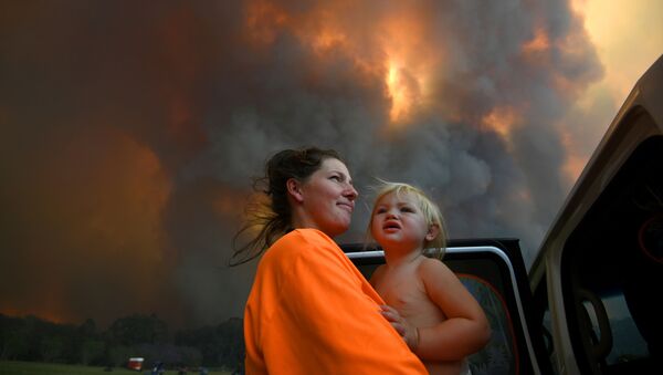 امرأة وطفلتها تنظران إلى الدخان الكثيف المتصاعد من حرائق الغابات بالقرب من منطقة نانا غلين، بالقرب من ميناء كوفس، أستراليا، 12 نوفمبر 2019 - سبوتنيك عربي