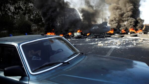 رجل ينام في سيارة بجوار إطارات محترقة على الطريق السريع خلال الاحتجاجات المستمرة المناهضة للحكومة في منطقة نهر الكلب، لبنان 13 نوفمبر 2019 - سبوتنيك عربي