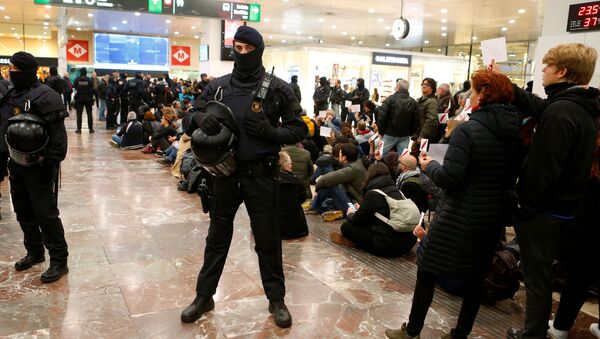 ضباط شرطة مكافحة الشغب يقفون حذرًا بينما يتظاهر المتظاهرون الانفصاليون الكاتالونيون داخل محطة قطار سانتس في برشلونة - سبوتنيك عربي