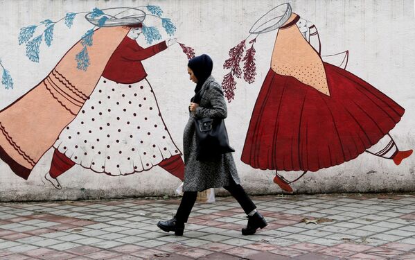 امرأة تسير على خلفية سور عليه جدارية في طهران، إيران 19 نوفمبر 2019 - سبوتنيك عربي