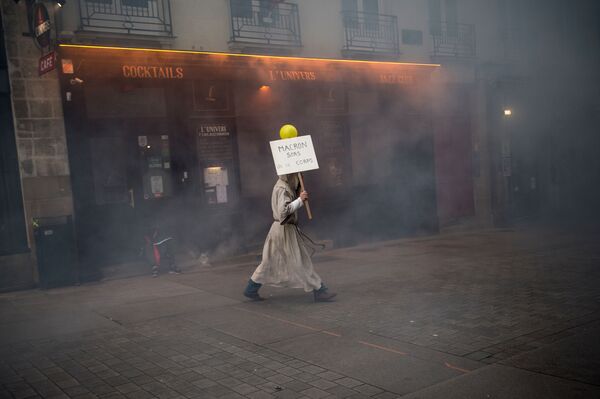 رجل يرتدي طاقم راهب ويحمل لافتة كتب عليها ماكرون، اخرج من هذا الجسد!، خلال مظاهرة لإحياء مرور الذكرى الأولى لانطلاق احتجاجات السترات الصفراء في فرنسا، نونت، 16 نوفمبر 2019 - سبوتنيك عربي