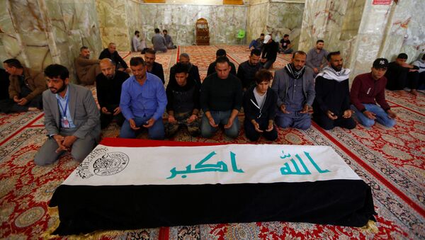 مشيعون يصلون بجوار نعش أحد المتظاهرين الذين قُتلوا في احتجاجات مناهضة للحكومة في الناصرية أثناء تشييع جنازته في النجف - سبوتنيك عربي
