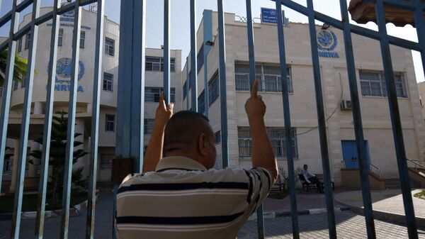 رجل فلسطيني يقف خارج البوابة المغلقة لوكالة غوث وتشغيل اللاجئين الفلسطينيين (الأونروا) - سبوتنيك عربي