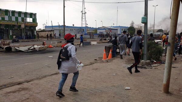 المتظاهرون يجمعون أغلفة الطلقات أثناء المظاهرات في ذي قار العراقية - سبوتنيك عربي