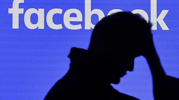 رجل يمر بجانب شاشة فيسبوك - سبوتنيك عربي