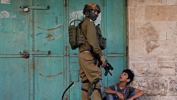 جندي إسرائيلي يحتجز طفلاً فلسطينياً خلال مظاهرة مناهضة لإسرائيل في الخليل بالضفة الغربية التي تحتلها إسرائيل - سبوتنيك عربي