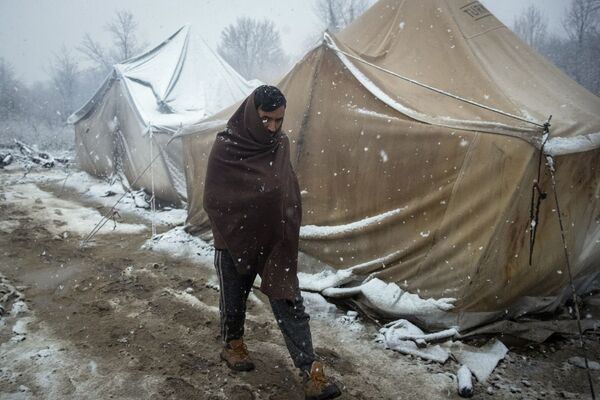 رجل، لاجئ، يسير بين خيام للاجئين بالرغم من بدء البرد وتساقط الثلج في مخيم للاجئين فوجاك، شمال غرب البوسنة، 2 ديسمبر 2019 - سبوتنيك عربي