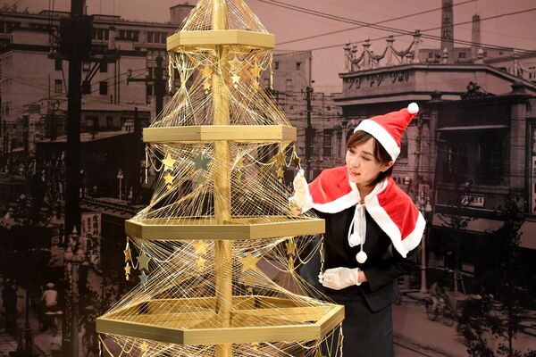 موظفة في بيت المجوهرات الياباني جينزا تاناكا (Ginza Tanaka) تعرض شجرة عيد الميلاد الذهبية التي تقدر بثمن 1.8 مليون دولار في طوكيو، 2016 - سبوتنيك عربي