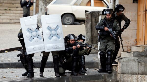 أفراد من شرطة الحدود الإسرائيلية يوجهون أسلحتهم إلى المتظاهرين الفلسطينيين خلال احتجاج على قرار الولايات المتحدة بشأن المستوطنات اليهودية في الخليل في الضفة الغربية التي تحتلها إسرائيل - سبوتنيك عربي