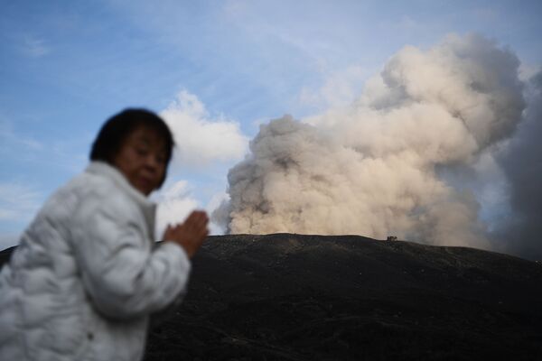 امرأة على خلفية بركان نشط في مدينة آسو في محافظة كوماموتو، اليابان 14 ديسمبر 2019 - سبوتنيك عربي