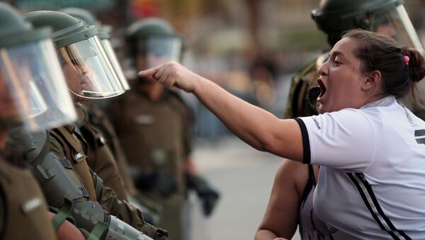 امرأة تصرخ على شرطي خلال احتجاجات مناهضة للحكومة في سانتياغو، تشيلي 15 ديسمبر 2019 - سبوتنيك عربي