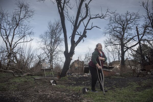 مواطنة تقف بالقرب من ركام منزل تعرض للقصف الصاروخي في بلدة نوفوأزوفسك في جمهورية دونيتسك الشعبية، أوكرانيا 15 ديسمب 2019 - سبوتنيك عربي