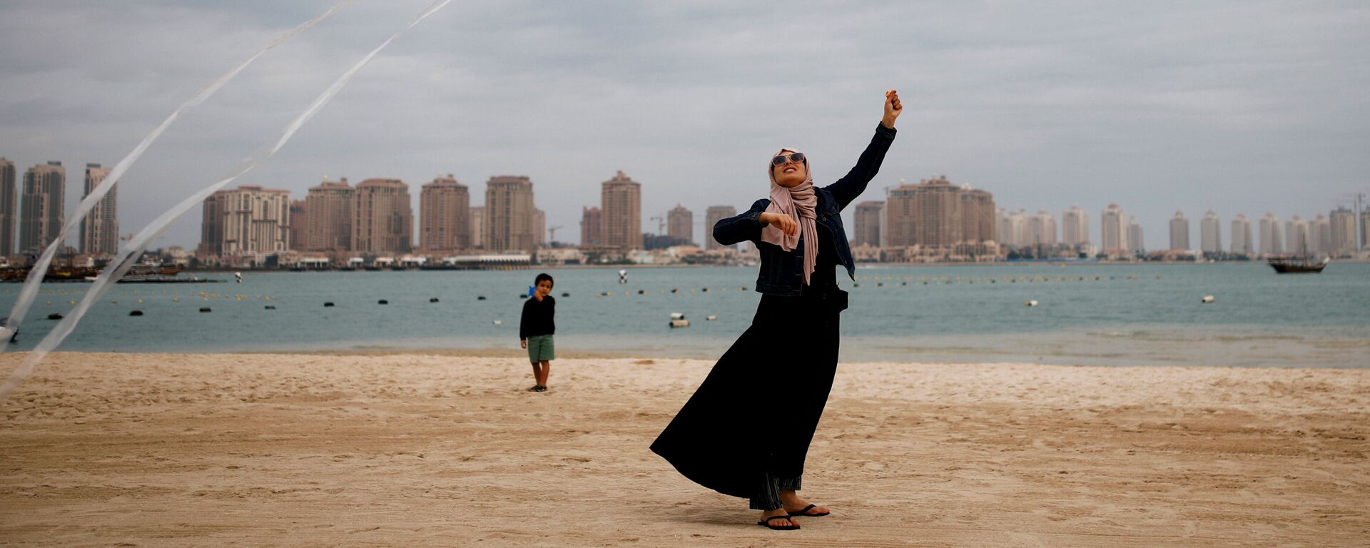 امرأة تطلق طيقا ورقيا على شاطئ كتارا في الدوحة، قطر 13 ديسمبر 2019 - سبوتنيك عربي, 1920, 14.10.2020