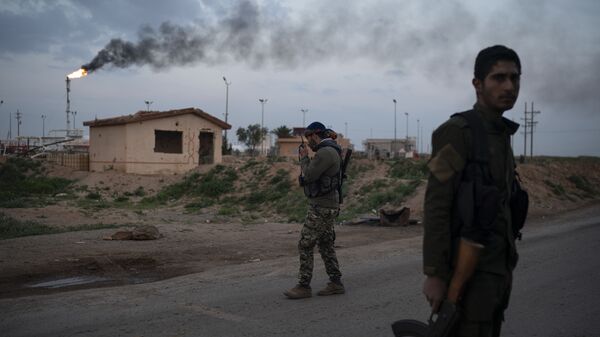 أحد مقاتلي قوات سوريا الديمقراطية المدعومة من الولايات المتحدة يتحدث عبر جهاز إرسال عند نقطة تفتيش بالقرب من حقل عمر النفطي شرق سوريا - سبوتنيك عربي