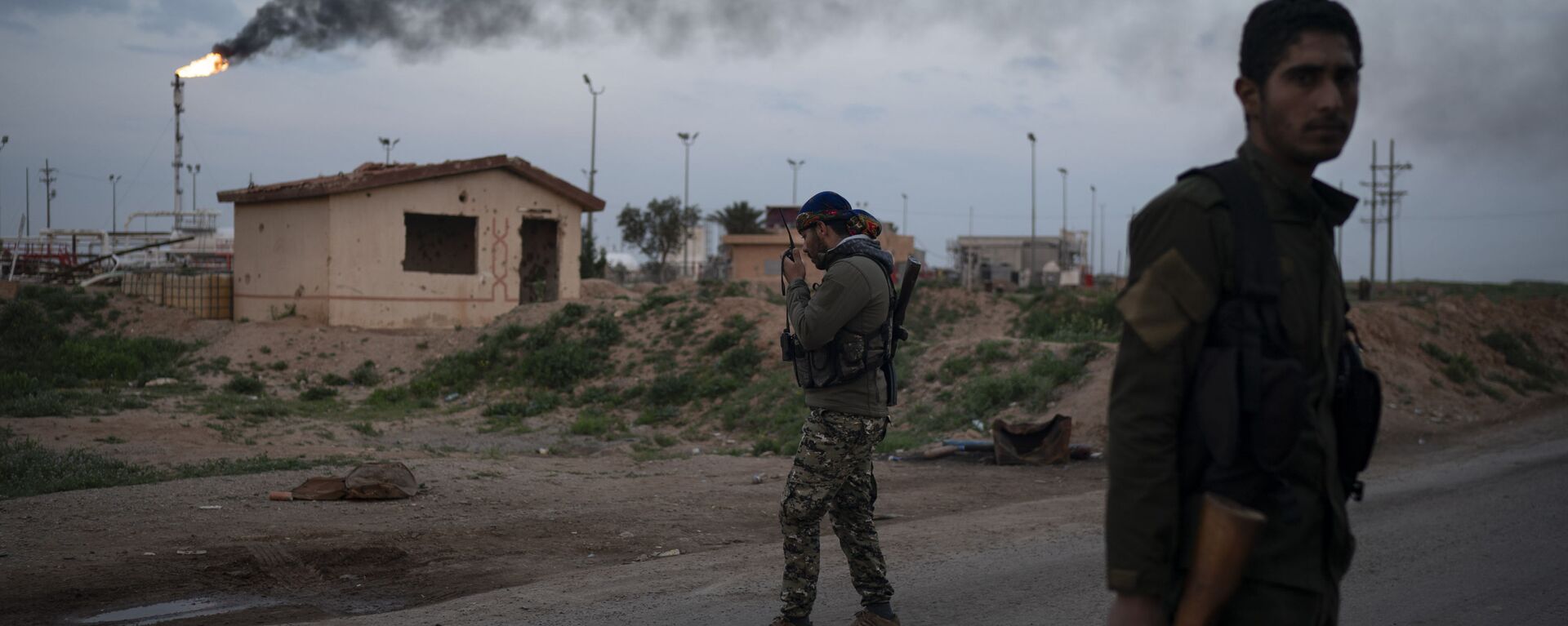 أحد مقاتلي قوات سوريا الديمقراطية المدعومة من الولايات المتحدة يتحدث عبر جهاز إرسال عند نقطة تفتيش بالقرب من حقل عمر النفطي شرق سوريا - سبوتنيك عربي, 1920, 30.11.2022