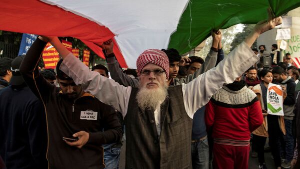 متظاهرون يحملون العلم الوطني للهند أثناء حضورهم احتجاجًا على قانون الجنسية الجديد خارج جامعة الجامعة الإسلامية في نيودلهي - سبوتنيك عربي
