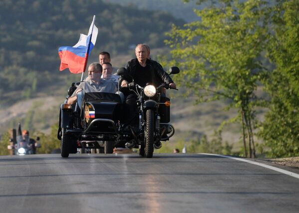 الرئيس الروسي فلاديمير بوتين يشارك في مسيرة للدراجات النارية الذئاب الليلية التي ينظمها نادي الدراجات النارية الذئاب الليلية (نوتشنيه فولكي) في سيفاستوبول يقود دراجة نارية من طراز أورال مع مركبة، 10 أغسطس 2019 - سبوتنيك عربي