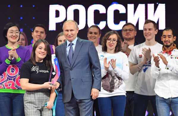 الرئيس الروسي فلاديمير بوتين يقدم الجائزة للفائزة، إنيسا كليوكينا، في مسابقة عموم روسيا التطوع لروسيا 2019 في ترشيح تطوع العام في ختام فعاليات منتدى متطوع روسيا، 5 ديسمبر 2019 - سبوتنيك عربي