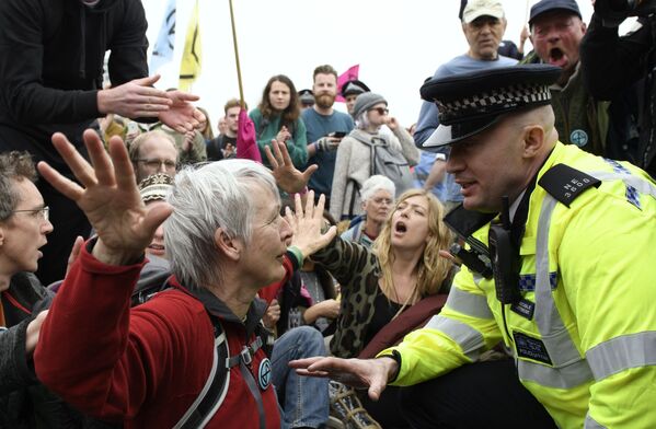 ضابط شرطة يتواصل مع أحد المشاركين في احتجاجات ضد التلوث البيئي في أحد شوارع لندن، إنجلترا 16 أبريل 2019 - سبوتنيك عربي
