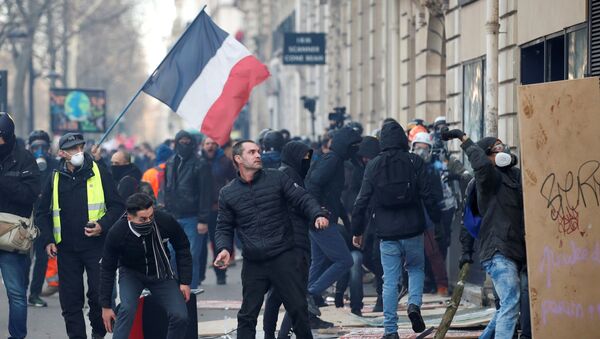متظاهر يحمل حجرا خلال مظاهرة لأعضاء النقابات العمالية والعمال الفرنسيين، 11 يناير/ كانون الثاني 2020 - سبوتنيك عربي