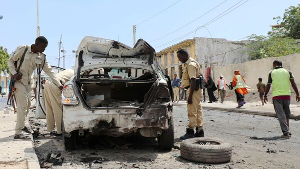 شرطي يقيم حطام سيارة في مكان انفجار قنبلة في شارع مكة المكرمة بمقديشو - سبوتنيك عربي