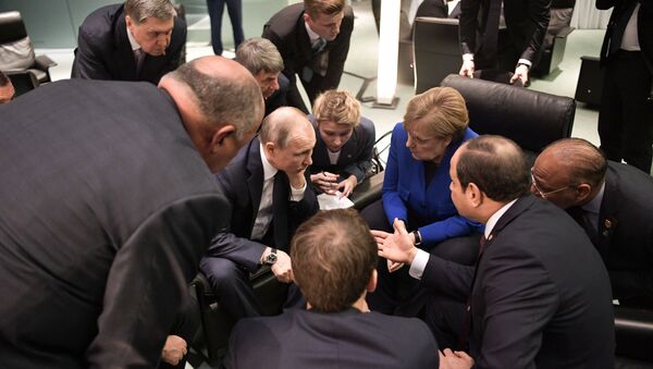 الرئيس الروسي فلاديمير بوتين والمستشارة الألمانية أنغيلا ميركل يتحدثان خلال اجتماع على هامش مؤتمر سلام دولي حول ليبيا في برلين - سبوتنيك عربي