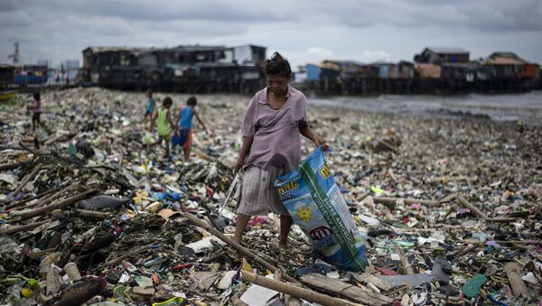 امرأة تجمع النفايات البلاستيكية على خليج مانيلا في الفلبين - سبوتنيك عربي