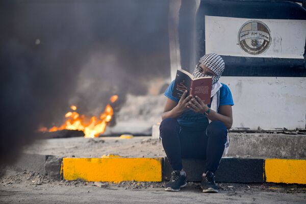 أحد المتظاهرين يقرأ كتبا خلال الاحتجاجات في النجف، العراق 19 يناير 2020 - سبوتنيك عربي