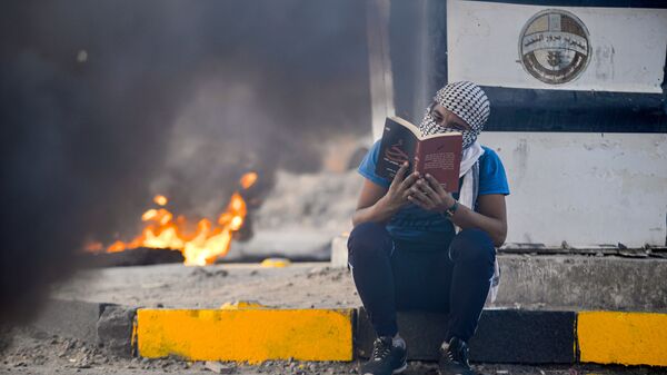 أحد المتظاهرين يقرأ كتبا خلال الاحتجاجات في النجف، العراق 19 يناير 2020 - سبوتنيك عربي