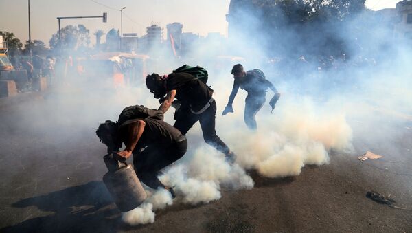 المتظاهرون يرمون الغاز المسيل للدموع مرة أخرى خلال الاحتجاجات المستمرة المناهضة للحكومة في بغداد - سبوتنيك عربي
