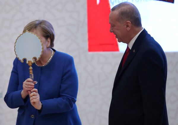المستشارة الألمانية أنغيلا ميركل تعبر عن سعادتها بالهدية التي قدمها لها الرئيس التركي رجب طيب أردوغان خلال مراسم افتتاح المباني الجديدة للجامعة التركية – الألمانية في إسطنبول، 24 يناير 2020 - سبوتنيك عربي