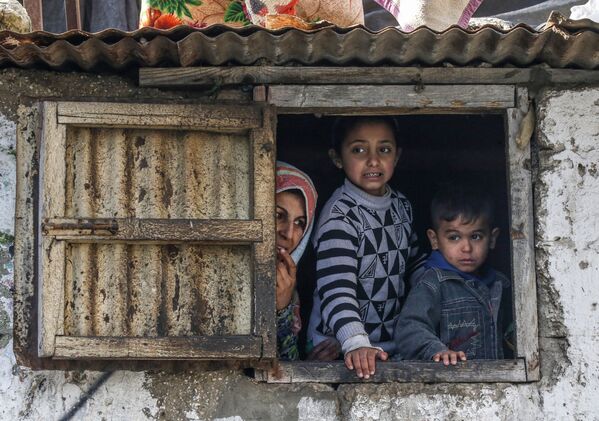 عائلة فلسطسنية في مخيم اللاجئين في خان يونس تطل من نافذة، جنوب قطاع غزة، فلسطين 28 يناير 2020 - سبوتنيك عربي