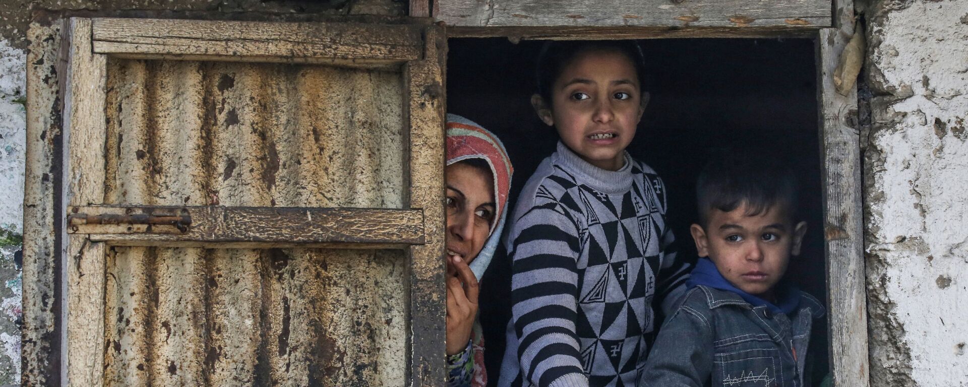 عائلة فلسطسنية في مخيم اللاجئين في خان يونس تطل من نافذة، جنوب قطاع غزة، فلسطين 28 يناير 2020 - سبوتنيك عربي, 1920, 13.12.2021