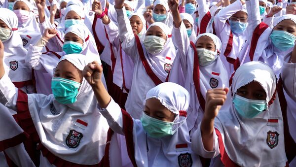 يرتدي الطلاب أقنعة الوجه أثناء إجراء الرعاية الصحية المخصص لفيروس كورونا في سولو في جافا الوسطى - سبوتنيك عربي