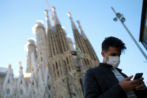 سائح صيني يرتدي قناعا واقيا بعد تأكيد حالات الإصابة بفيروس كورونا في إسبانيا، يلتقط صورة على خلفية كنيسة العائلة المقدسة في برشلونة (باسيليكا ساغري غدا فاميليا) 2 فبراير 2020 - سبوتنيك عربي