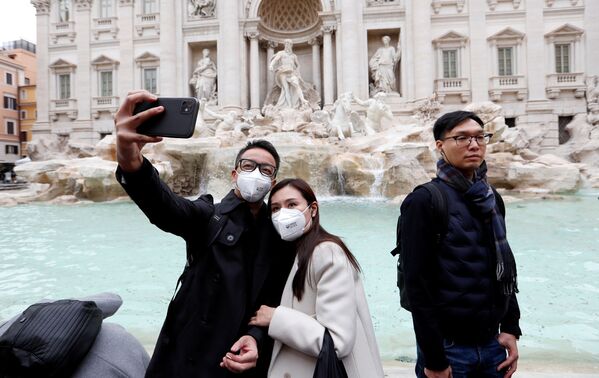 سياح يرتدون أقنعة واقية بعد تأكيد حالات الإصابة بفيروس كورونا في إيطاليا، يلتقطون صورة سيلفي على خلفية نافورة تريفي في روما، 31 يناير 2020 - سبوتنيك عربي