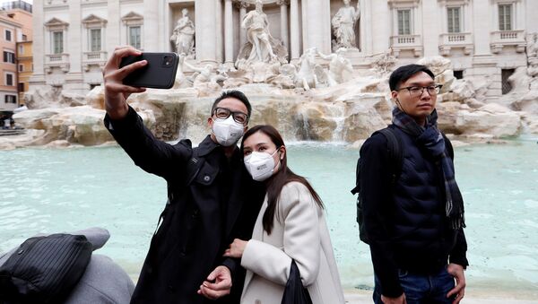 سياح يرتدون أقنعة واقية بعد تأكيد حالات الإصابة بفيروس كورونا في إيطاليا، يلتقطون صورة سيلفي على خلفية نافورة تريفي في روما، 31 يناير 2020 - سبوتنيك عربي